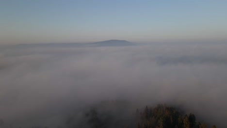 Volando-Sobre-Las-Nubes-Mostrando-El-Bosque-Y-La-Cima-De-La-Montaña