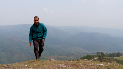 Mann,-Der-Auf-Berggipfel-Mit-Nebligem-Bergwuthintergrund-Aus-Flachem-Winkelvideo-Läuft,-Wird-In-Nongjrong-Meghalaya-Indien-Aufgenommen