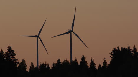Amanecer,-Silueta---Las-Turbinas-Eólicas-Salen-De-Un-Bosque,-Suecia