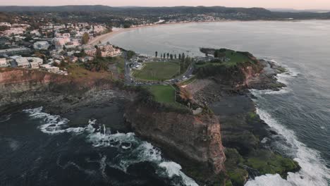 Sunrise-Drone-shot-at-the-cliffs-and-coastline-of-The-Skillion-in-Terrigal,-NSW,-Australia