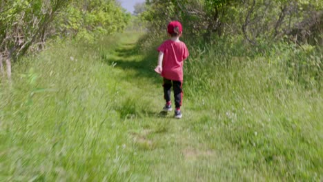 Eine-Bewegende-Aufnahme-Eines-Süßen-Kindes-In-Rotem-T-Shirt-Und-Mütze,-Das-Im-Schönen-Wald-Spielt