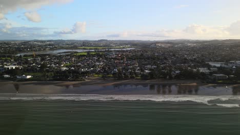 Zooming-out-on-sunset-at-Orewa-beach,-New-Zealand