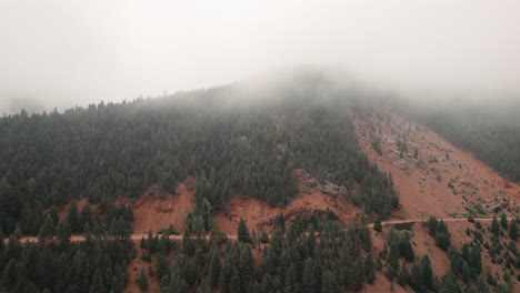 Aerial-dolly-in-over-misty-Cheyenne-Valley-and-forest-road-on-forested-peak
