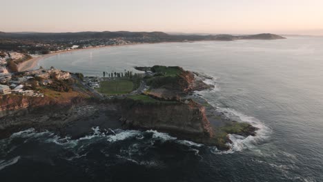 Sunrise-Drone-shot-at-the-cliffs-and-coastline-of-The-Skillion-in-Terrigal,-NSW,-Australia