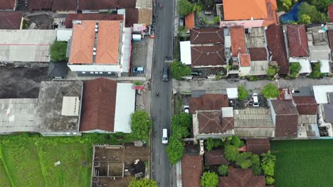 Luftaufnahme-Von-Motorrädern-Und-Autos-Auf-Der-Straße,-Die-An-Reisfeldern-In-Bali-Indonesien-Vorbeiführt