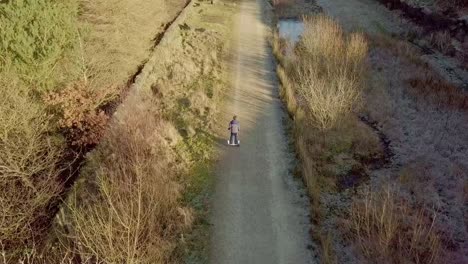 Young-boy-riding-down-a-country-pathway-on-a-hoverboard