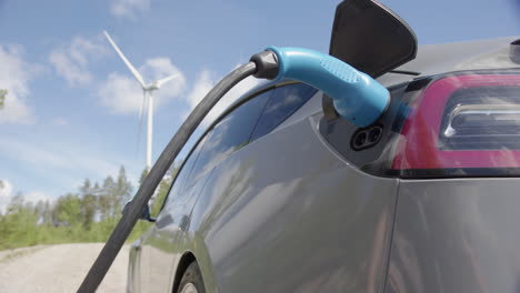 SLIDER---A-generic-electric-vehicle-is-plugged-in,-wind-turbine-behind