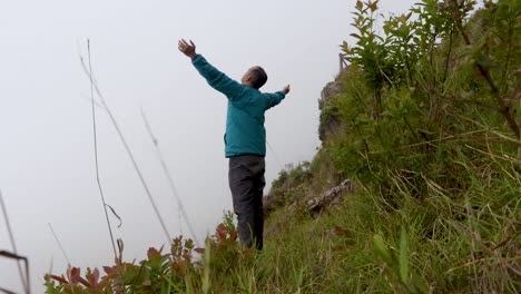 man-alone-at-mountain-rock-with-white-mist-background-from-flat-angle
