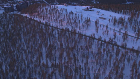 Stunning-tilt-up-aerial-shot-of-Levi-ski-slopes-at-sunset,-Kittila,-Finland