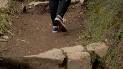 Young-girl-legs-in-sneakers-walking-on-a-path-climbing-some-stone-steps