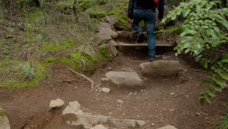 Man-photographer-hiker-with-backpack-and-tripod-walking-on-a-path-climbing-some-stone-steps