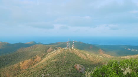 Cell-towers-on-distant-hilltop-in-Curacao,-Caribbean-with-storm-clouds-gathering