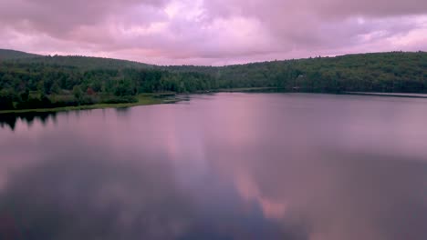DRONE-FLY-BY-of-shore-on-Monson-Pond,-Maine-at-sunset