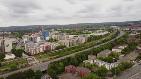 Drone-panning-left-to-right-tracking-train-go-through-Hendon,-North-London-UK-town,-during-day-time-cloudy