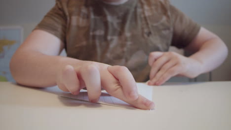 young-boy-folding-a-paper-airplane