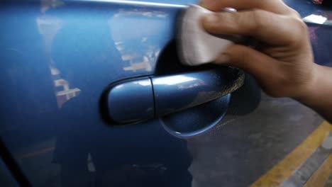 A-man-applying-clay-bar-to-the-door-and-handle-of-a-car