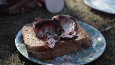 Rising-shot-of-bacon-sandwich-cooked-during-camping-holiday