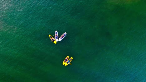 A-group-of-friends-chat-with-each-other-while-sitting-on-paddle-boards-on-the-water