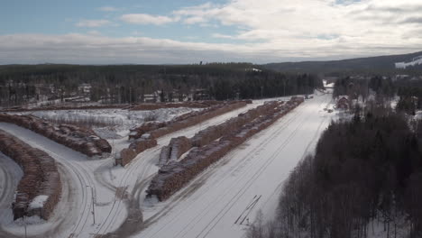 Cinematic-aerial-shot-of-a-huge-timber-yard-in-the-snow
