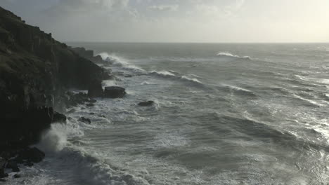 Cinematic-dawn-shot-of-waves-hitting-the-coast-in-Cornwall,-England