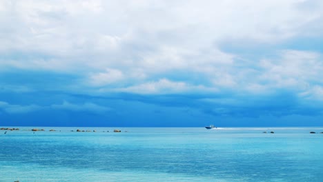 Boat-sailing-across-vibrant-blue-Caribbean-Sea-before-storm,-Slow-Motion-Pan