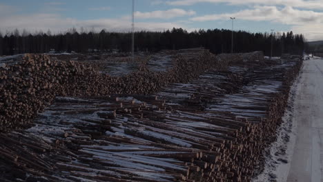 Cinematic-aerial-shot-of-stacked-timber-in-the-snow