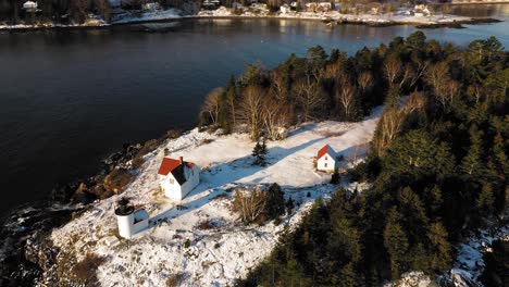Aerial-ORBIT-over-a-snow-covered-Curtis-Island-Lighthouse-at-sunrise-with-long-shadows-in-the-snow