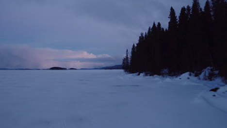 Cinematic-aerial-shot-at-dusk-along-a-frozen-shoreline