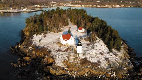 Close-up-Aerial-ORBIT-over-a-snow-covered-Curtis-Island-Lighthouse-at-sunrise-with-long-shadows-in-the-snow