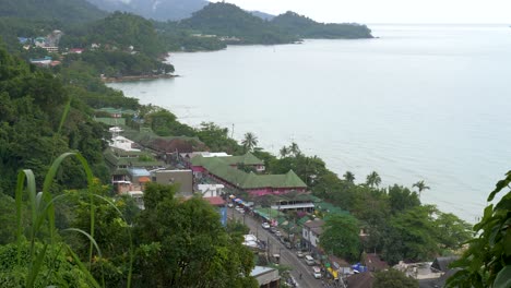 Zoom-out-shot,-of-a-small-town,-at-white-sand-beach,-on-a-cloudy-day,-in-Koh-Kood,-Thailand,-Asia