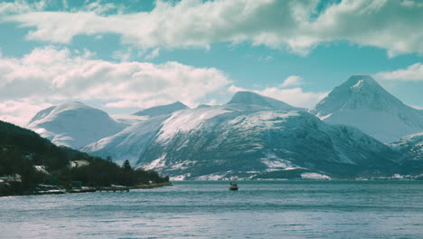 Stunning-shot-of-a-boat-on-Lyngen-fjord,-with-mountains-behind