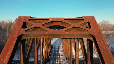 Aerial-CRANE-down-close-up-of-a-rusty-railroad-trestle-on-a-cold-winter-morning