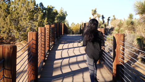 A-girl-with-long-black-hair-runs-across-a-wooden-bridge-in-the-desert-in-slow-motion