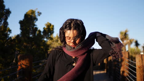 A-pretty-girl-with-long-black-hair-putting-on-a-red-warm-scarf-in-slow-motion-on-a-cold-autumn-morning