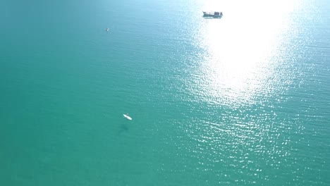 Aerial,-top-down,-birdseye,-drone-shot-of-a-man-running-on-a-wooden-pier-and-people-swimming-in-the-turquoise-sea,-at-a-paradise-beach,-on-a-sunny-day,-in-Koh-Kood,-Thailand,-Asia