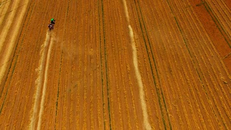 Aerial-birds-eye-view-of-a-tractor-dusting-crops-in-a-dry-arid-field
