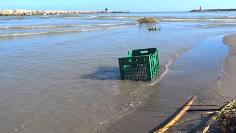 a-Plastic-crate-in-the-water-on-a-beach,-illustrating-the-seriousness-of-plastic-pollution-in-our-oceans