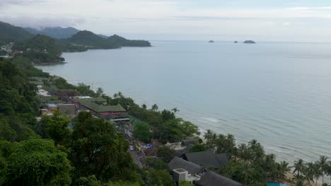 Zoom-out-shot,-of-a-small-town,-at-white-sand-beach,-on-a-cloudy-day,-in-Koh-Kood,-Thailand,-Asia