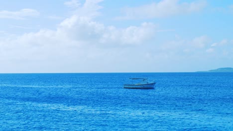 Small-fishing-boat-coming-into-shore-across-the-ocean-on-a-beautiful-sunny-day-in-Curacao