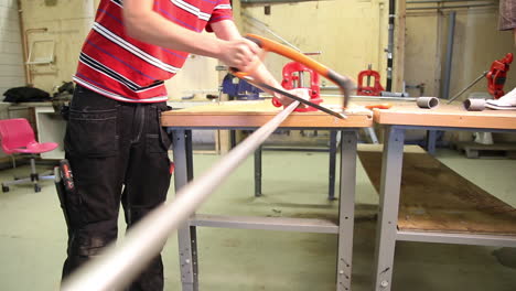 Close-up-of-a-young-male-intern-sawing-an-iron-bar-with-a-in-a-workshop