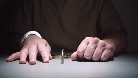Close-up-of-a-prisoner's-hands-while-he-sits-calmly-handcuffed-to-a-table-in-an-interrogation-room