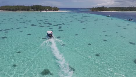 Crystal-clear-blue-waters-of-Mauritius-Island-on-vacation,-with-a-tourist-motor-boat-gliding-through-the-ocean-waters