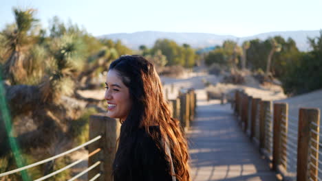 A-beautiful-girl-model-smiling-and-laughing-hard-as-she-tries-to-compose-herself-for-a-photo-shoot-in-the-desert-with-Joshua-trees-in-slow-motion