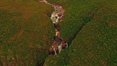 Aerial-tilting-up-over-a-river-flowing-into-a-waterfall-in-the-South-American-countryside