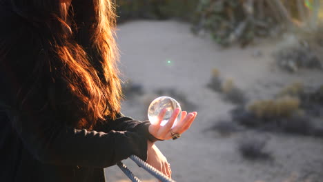 Close-up-on-the-hands-of-a-beautiful-woman-wearing-a-ring-and-holding-a-magic-crystal-ball-in-the-bright-sunlight-during-golden-hour-sunset