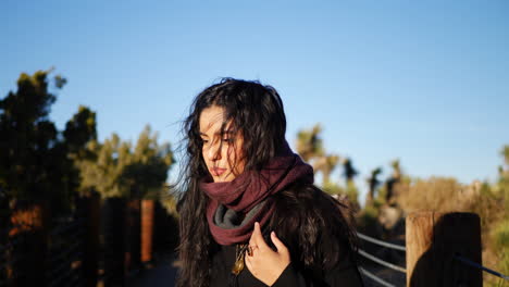 A-beautiful-girl-with-long-black-hair-adjusting-her-red-scarf-in-slow-motion-on-a-hike-in-autumn-desert