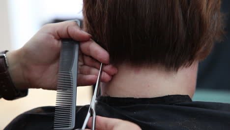 Close-up-view-of-a-hairdresser's-hands-cutting-hair-with-a-pair-of-scissors-at-a-hair-saloon