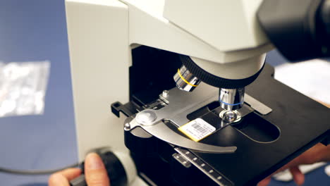 A-scientist-examining-a-slide-of-human-cells-with-a-microscope-in-a-medical-research-science-laboratory