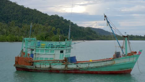 A-static-shot-of-an-old-fisherman-boat,-anchored-at-sea-near-an-island-Cropped