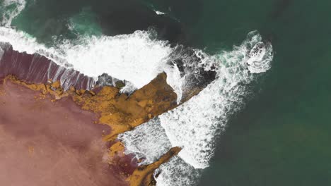 Stetige-Luftaufnahme-Als-Wellen,-Die-An-Der-Meeresküste-Am-Roten-Strand-Einbrechen